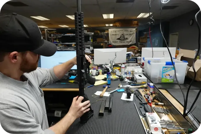 FirearmLand staff inspecting a rifle at the workbench in the Jacksonville shop